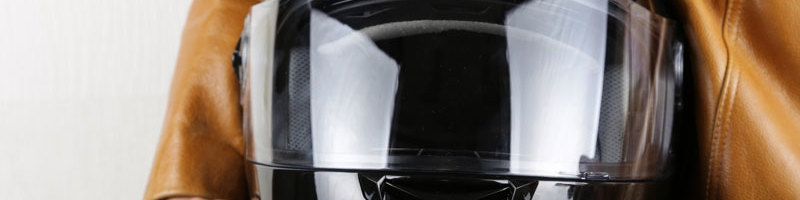 Black scooter helmet next to a brown leather jacket